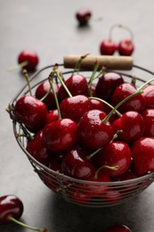 Photo of Metal basket with ripe sweet cherries on grey table, closeup