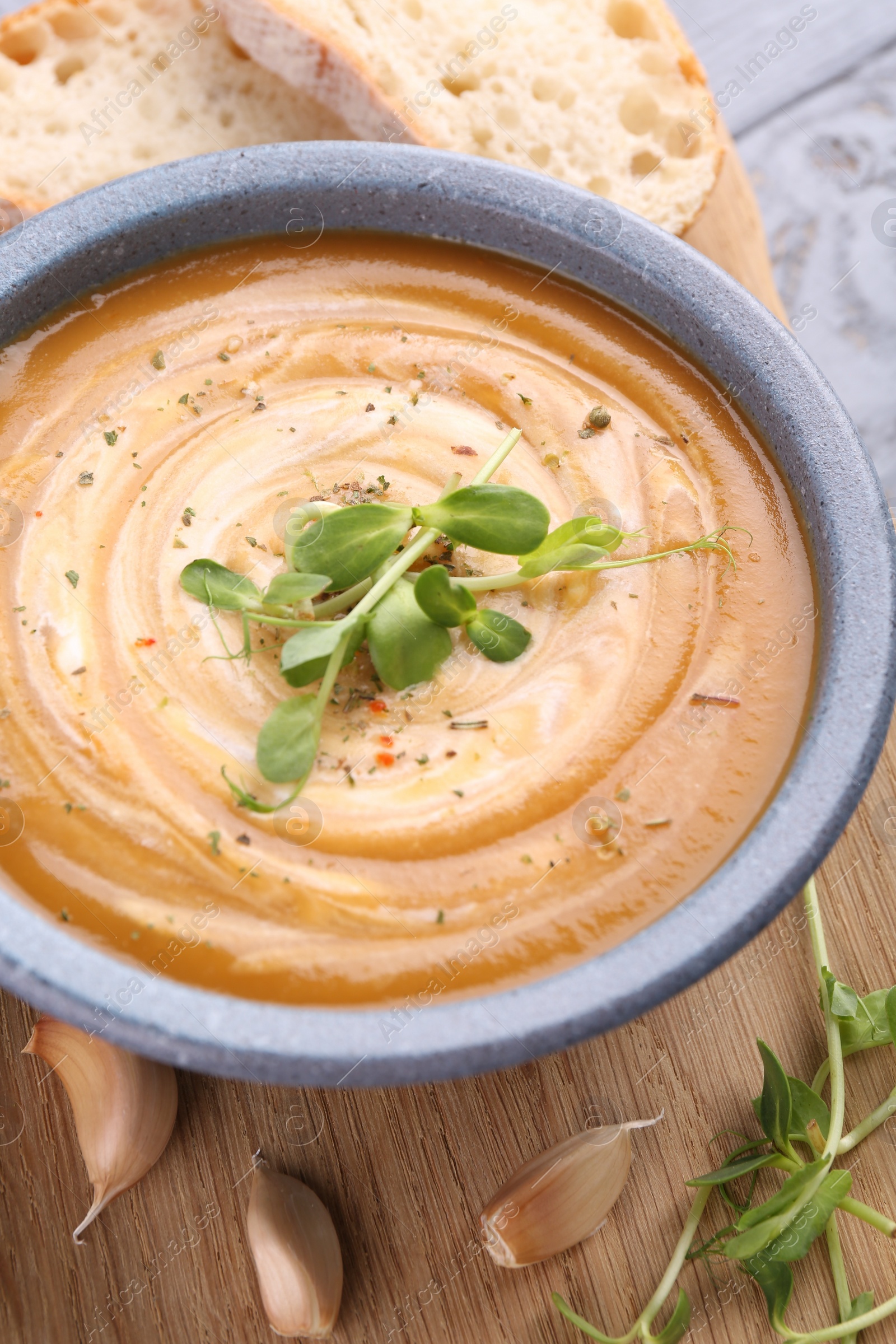 Photo of Tasty pumpkin soup with microgreens served on table, closeup