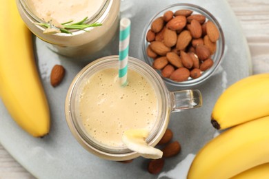 Photo of Tasty banana smoothie and ingredients on white wooden table, flat lay
