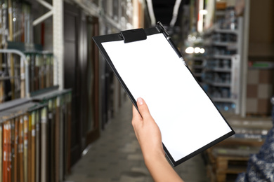 Photo of Woman with clipboard in wholesale warehouse, closeup. Space for text