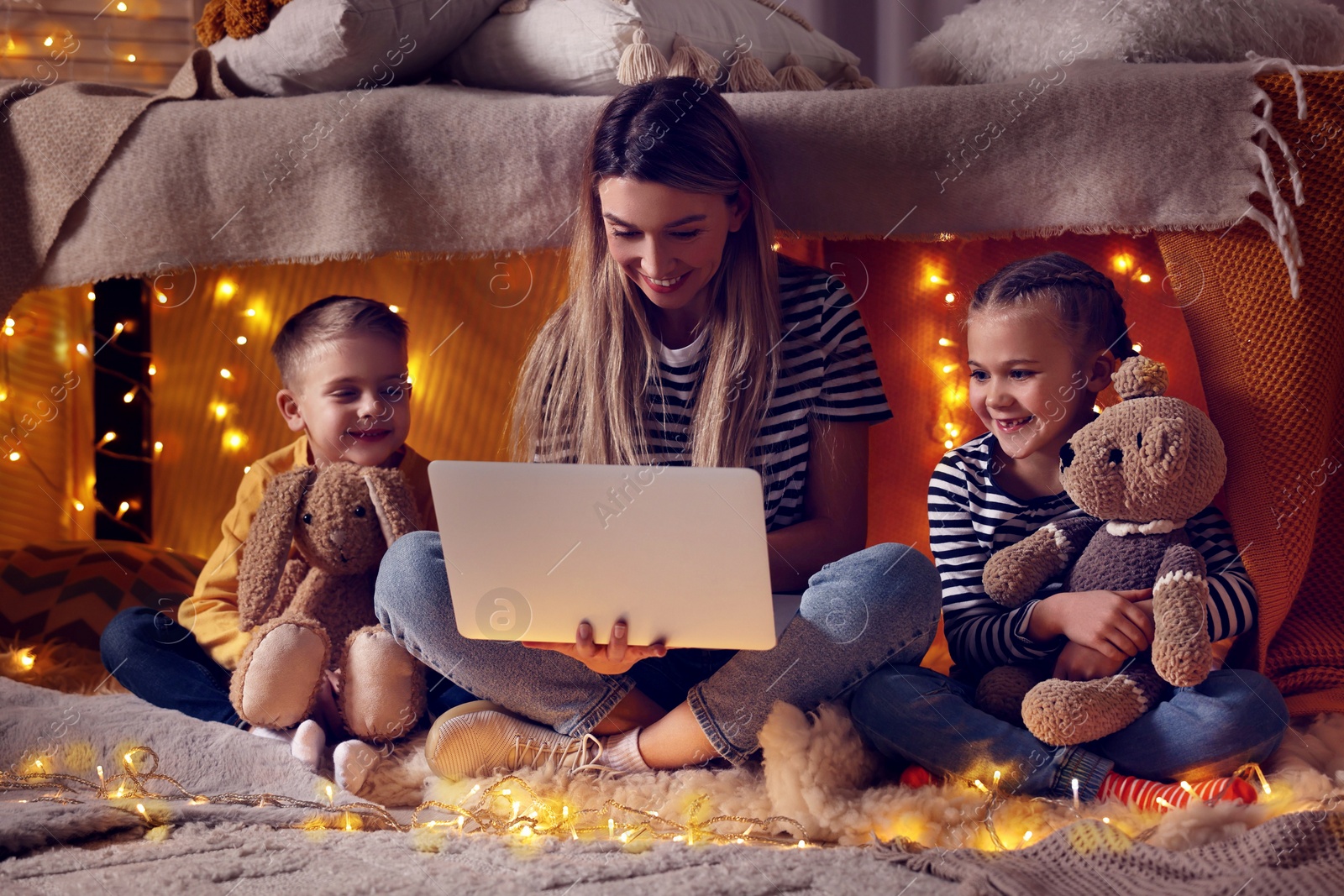 Photo of Mother and her children with laptop in play tent at home