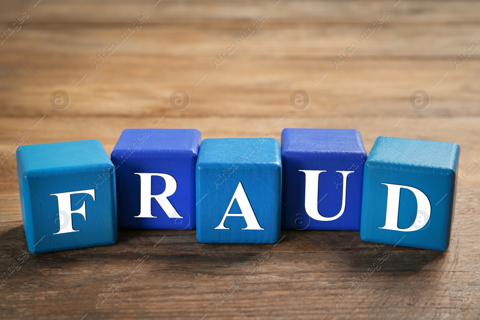 Photo of Word Fraud of cubes with letters on wooden background