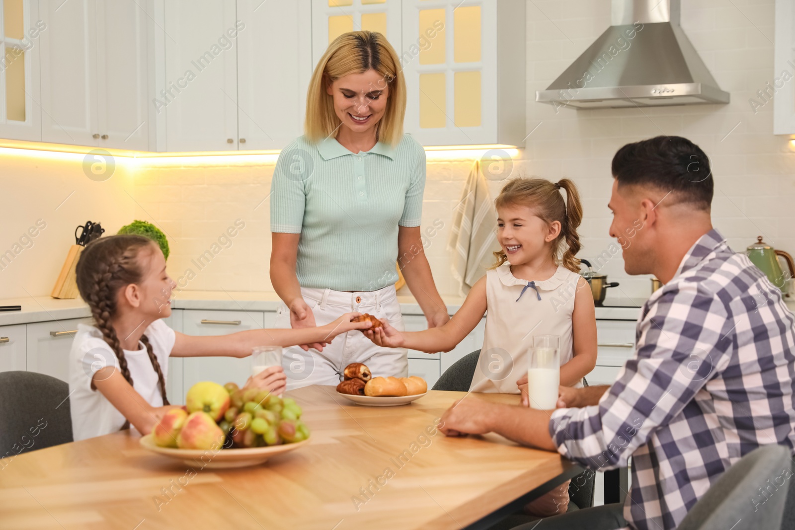 Photo of Happy family eating together at table in modern kitchen