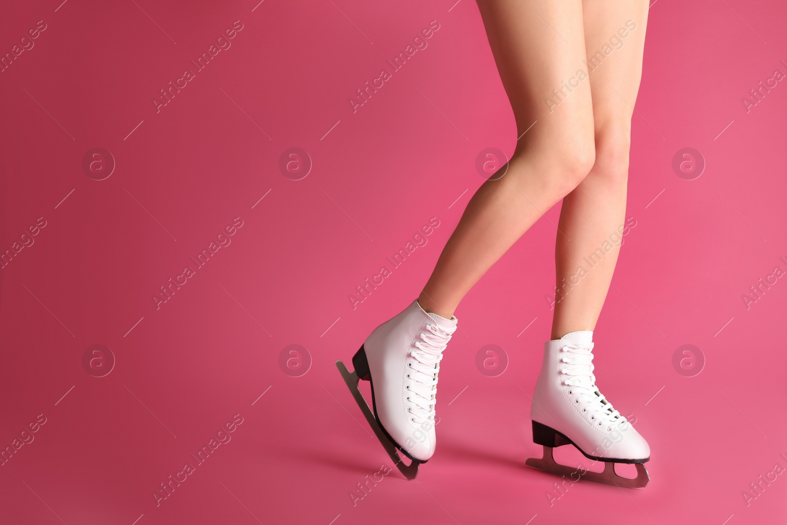 Photo of Woman in elegant white ice skates on pink background, closeup of legs. Space for text