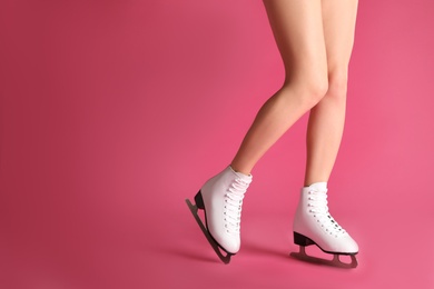 Photo of Woman in elegant white ice skates on pink background, closeup of legs. Space for text