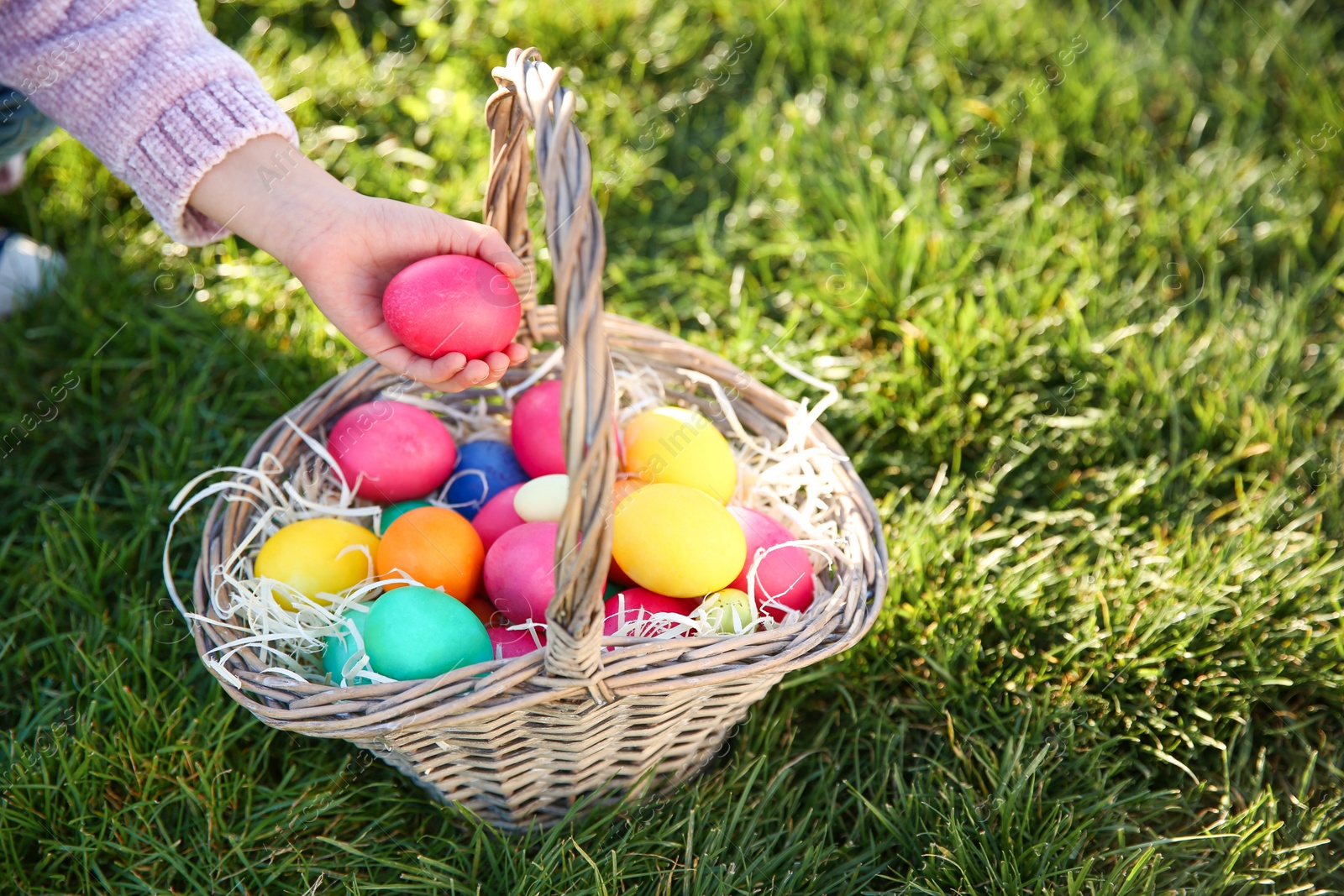 Photo of Little child with basket of Easter eggs in park, closeup. Space for text