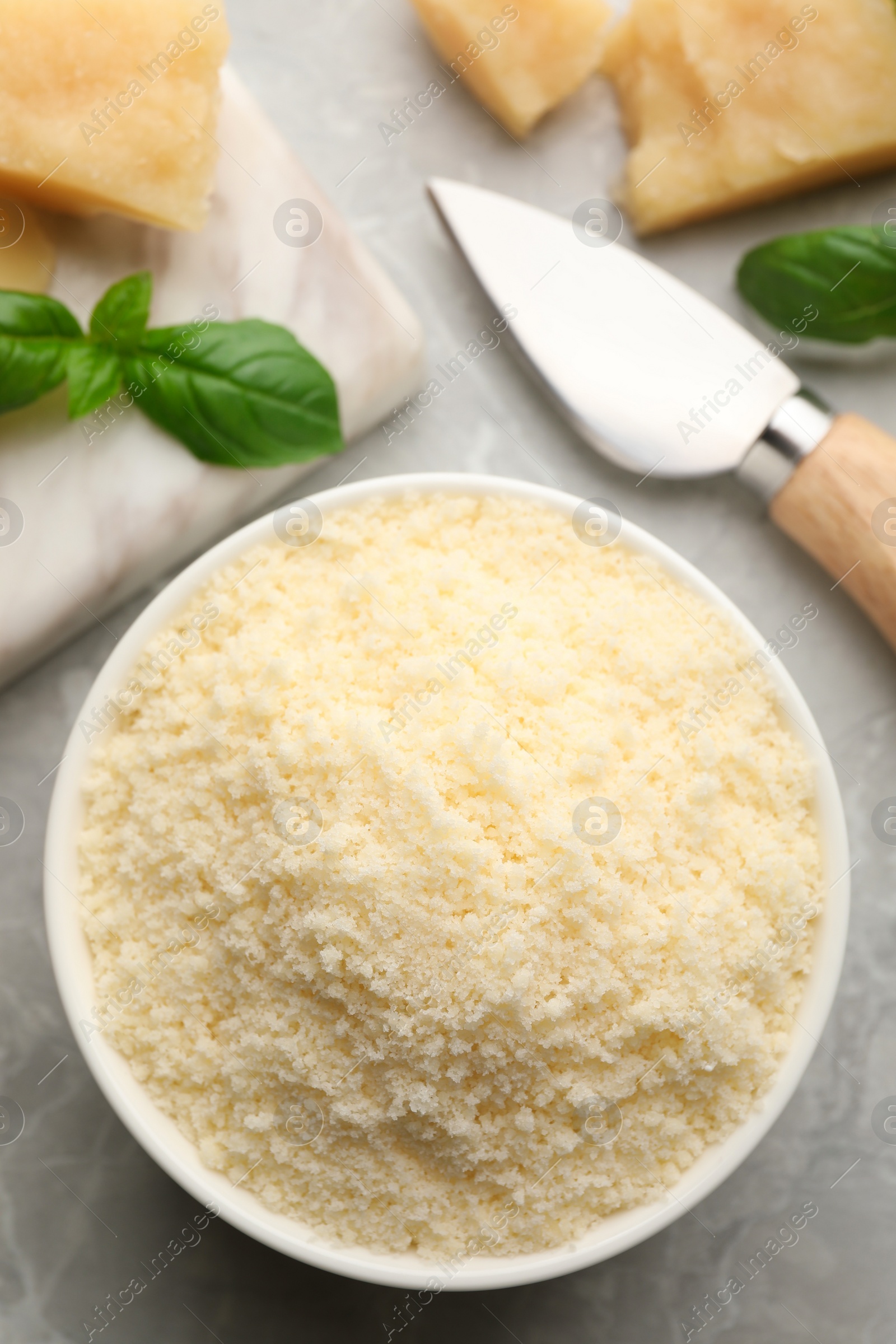 Photo of Bowl with grated parmesan cheese on light table, flat lay