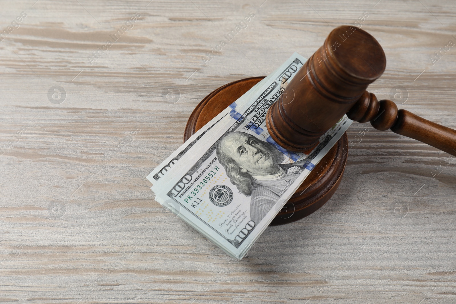 Photo of Judge's gavel and money on wooden table. Space for text