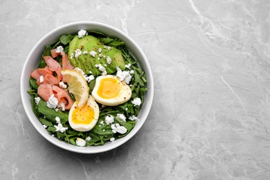 Delicious salad with boiled egg, salmon and cheese in bowl on light grey marble table, top view. Space for text