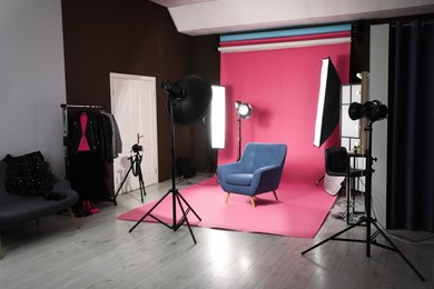 Photo of Stylish blue armchair in photo studio with professional equipment