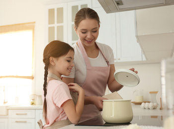 Mother and daughter cooking together in kitchen at home