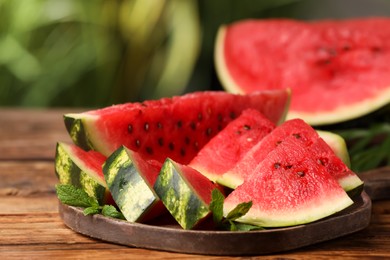 Photo of Slices of delicious ripe watermelon on wooden table outdoors, closeup