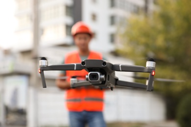 Photo of Builder operating drone with remote control at construction site, focus on quadcopter. Aerial survey