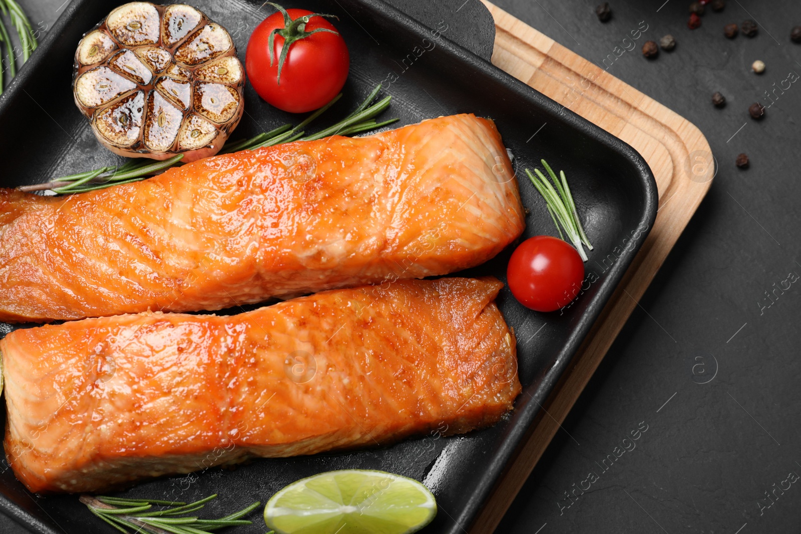 Photo of Delicious roasted fish served on black table, above view