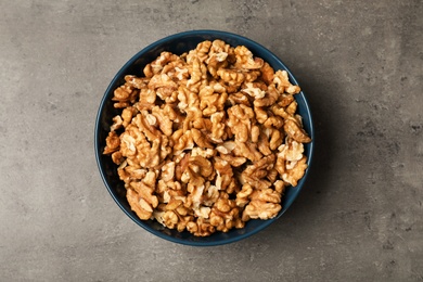 Dish with walnuts on grey background, top view