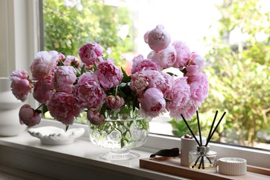 Beautiful pink peonies in vase on window sill. Interior design