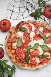 Photo of Delicious Caprese pizza with tomatoes, mozzarella and basil served on white table, flat lay