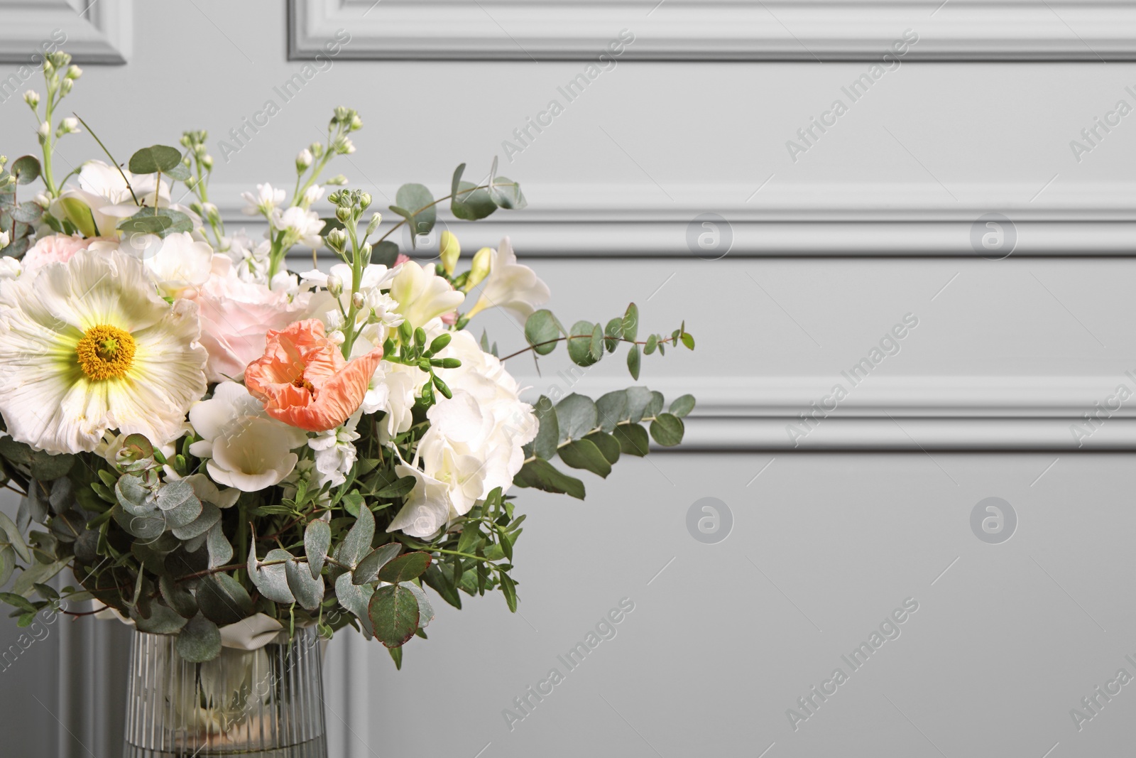 Photo of Bouquet of beautiful flowers near light wall, closeup. Space for text