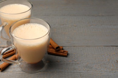 Delicious eggnog with cinnamon on grey wooden table. Space for text