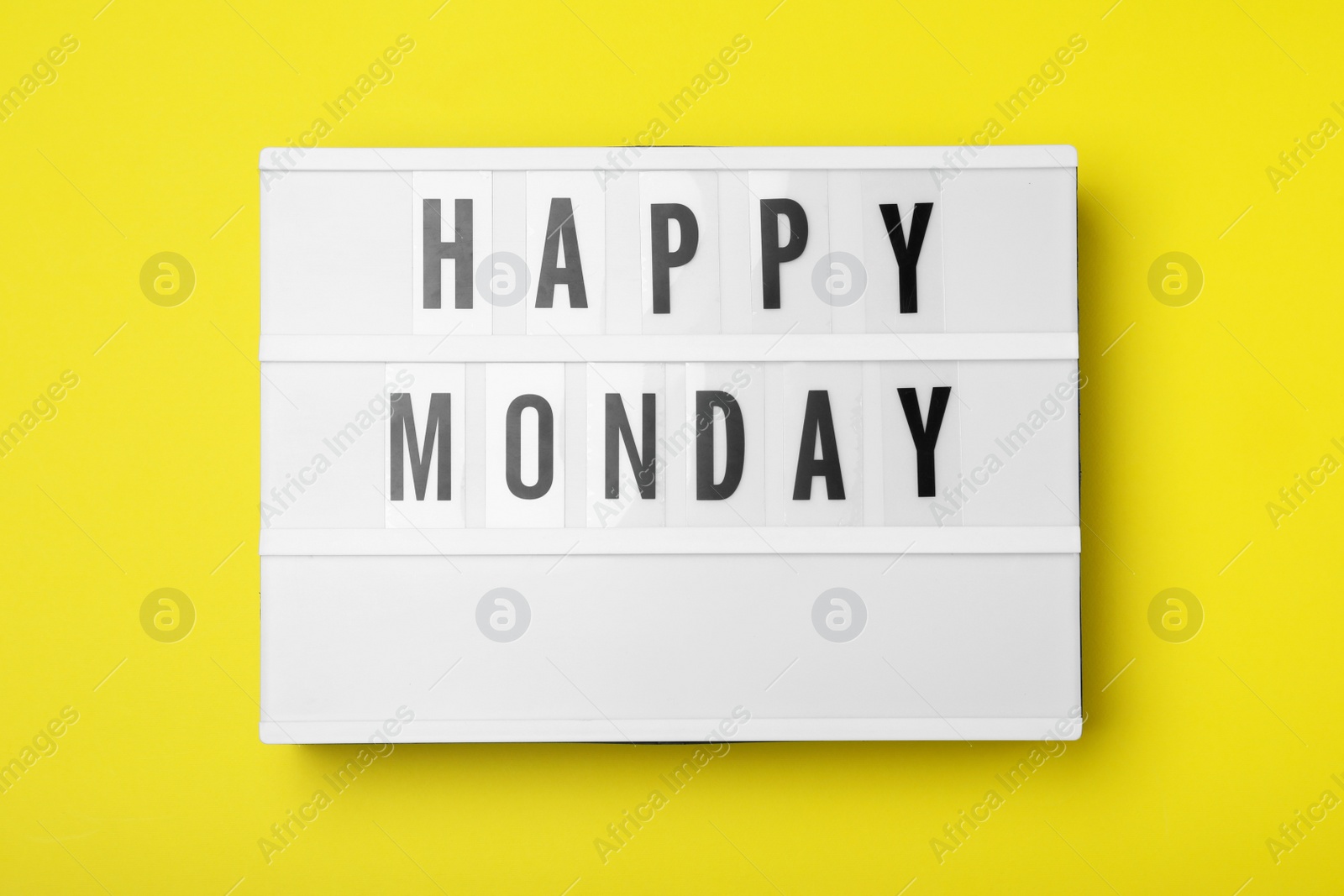 Photo of Light box with message Happy Monday on yellow background, top view