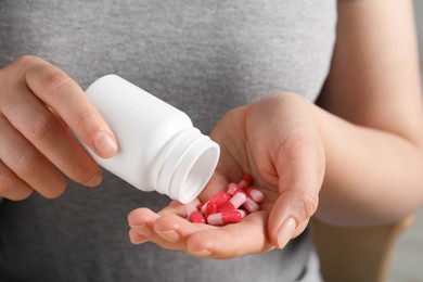 Woman pouring pills from bottle, closeup view