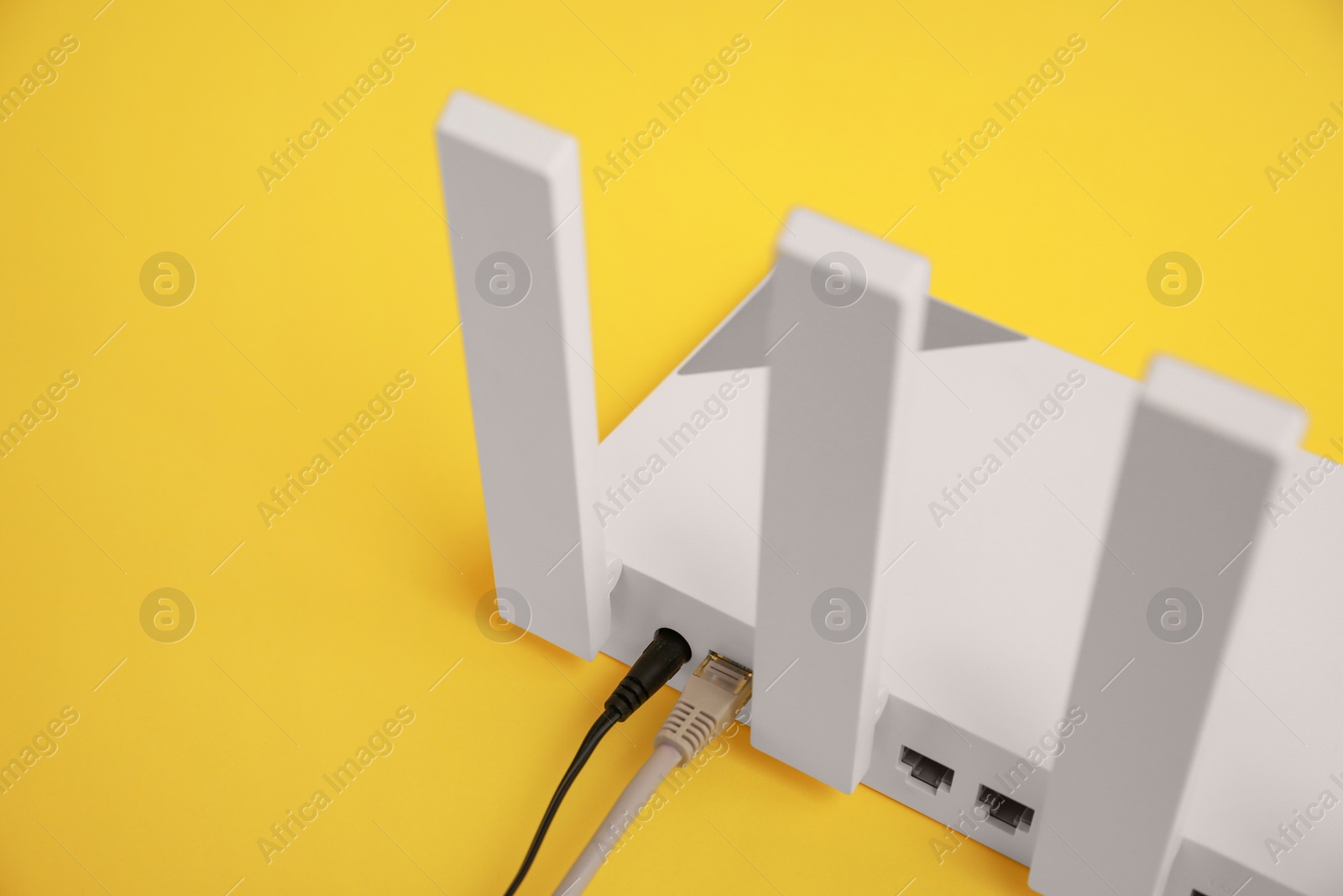 Photo of Modern Wi-Fi router on yellow background, closeup