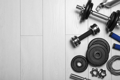 Photo of Gym equipment on wooden floor, flat lay. Space for text