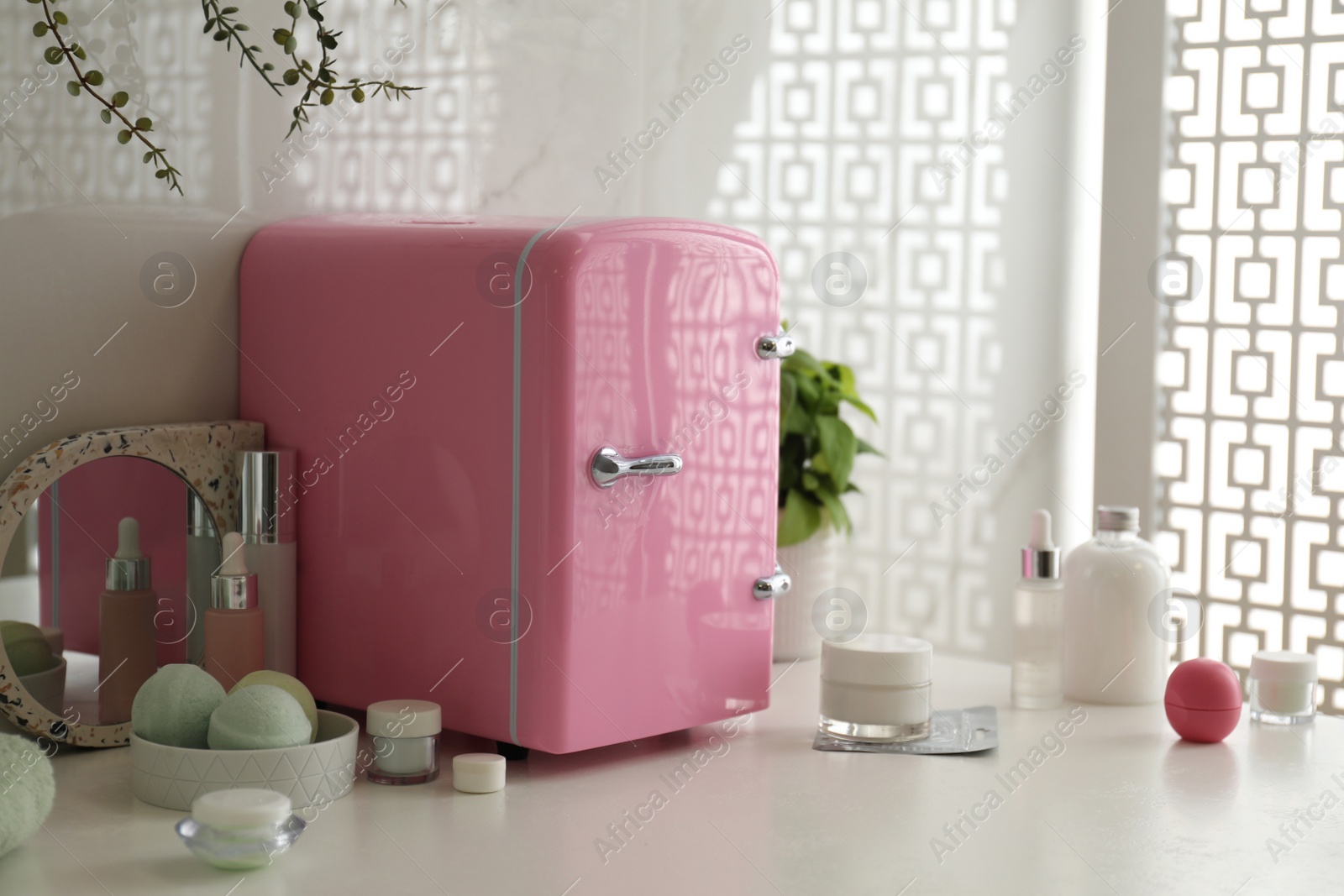 Photo of Cosmetics refrigerator and skin care products on white table indoors