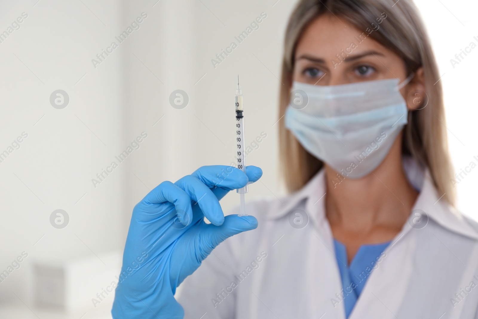 Photo of Doctor holding syringe with vaccine in hospital, focus on hand