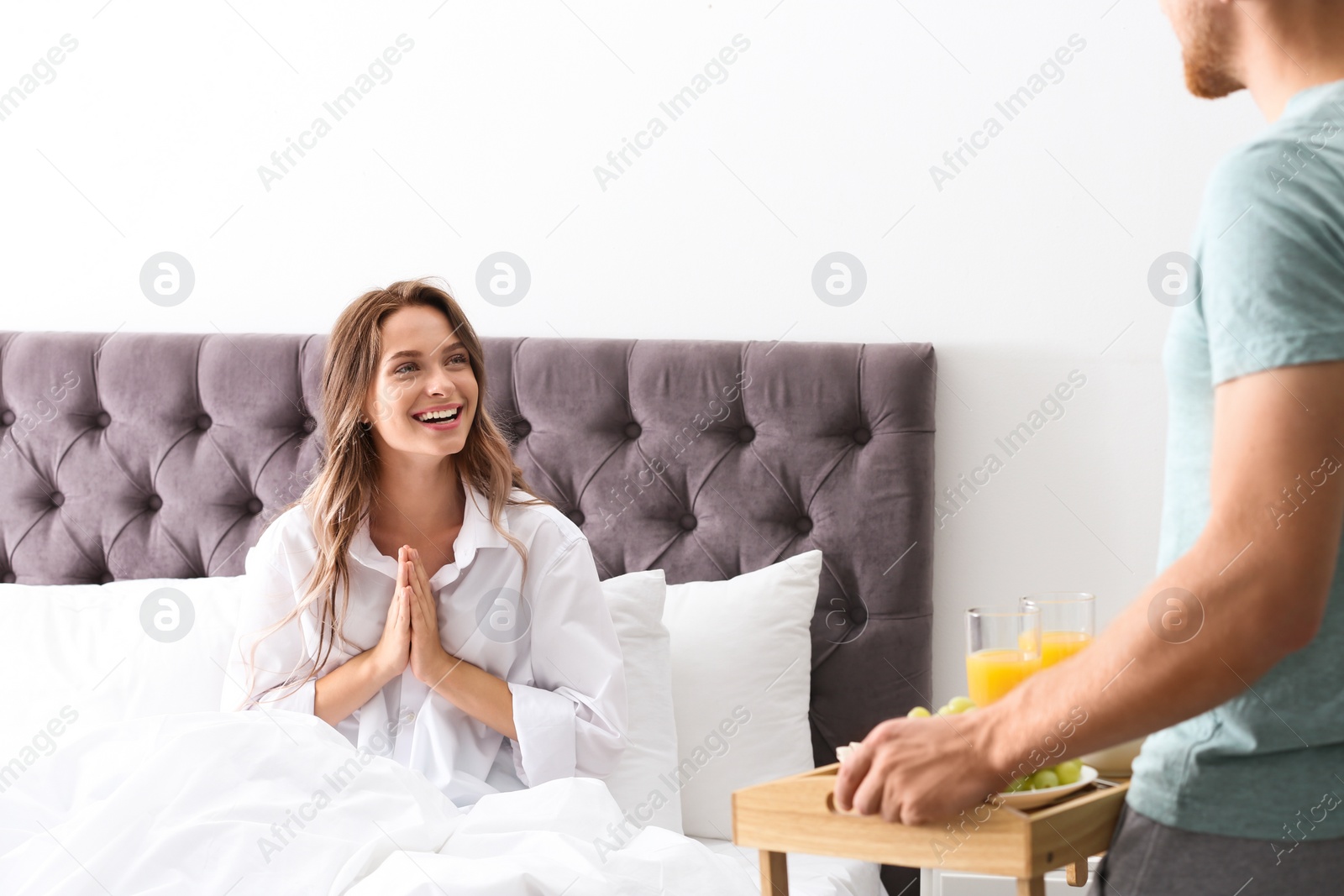 Photo of Young man bringing romantic breakfast to his girlfriend in bed at home