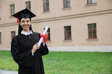 Photo of Happy student with diploma after graduation ceremony outdoors. Space for text