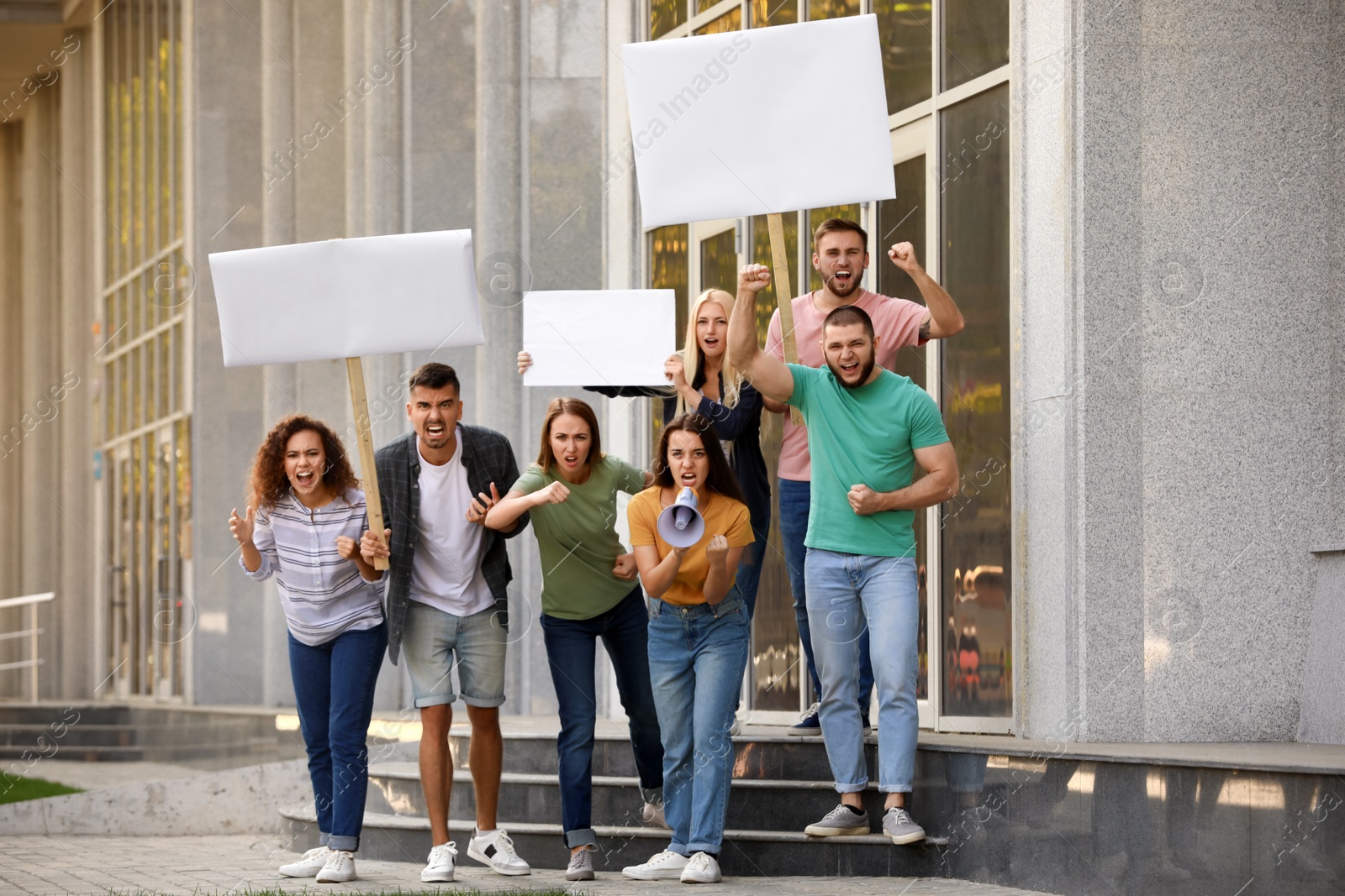 Photo of Angry young woman with megaphone leading protest outdoors