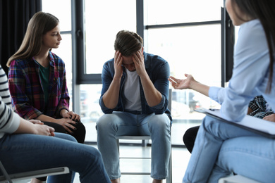 Psychotherapist working with patients in group therapy session indoors