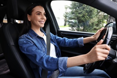 Photo of Woman with seatbelt holding steering wheel while driving her car