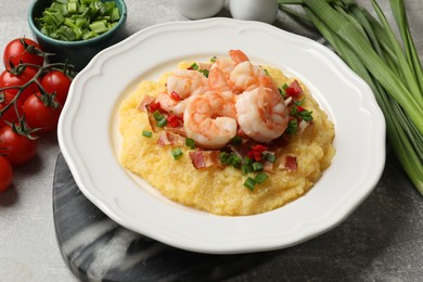 Photo of Plate with fresh tasty shrimps, bacon, grits, green onion and pepper on gray textured table, closeup