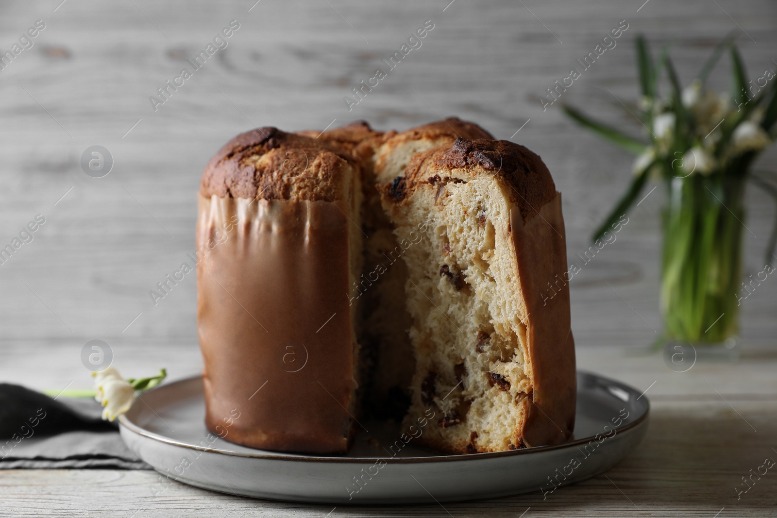 Photo of Delicious cut Panettone cake on light wooden table, closeup. Traditional Italian pastry
