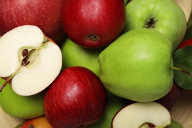 Photo of Fresh ripe apples and leaf on wooden plate, closeup