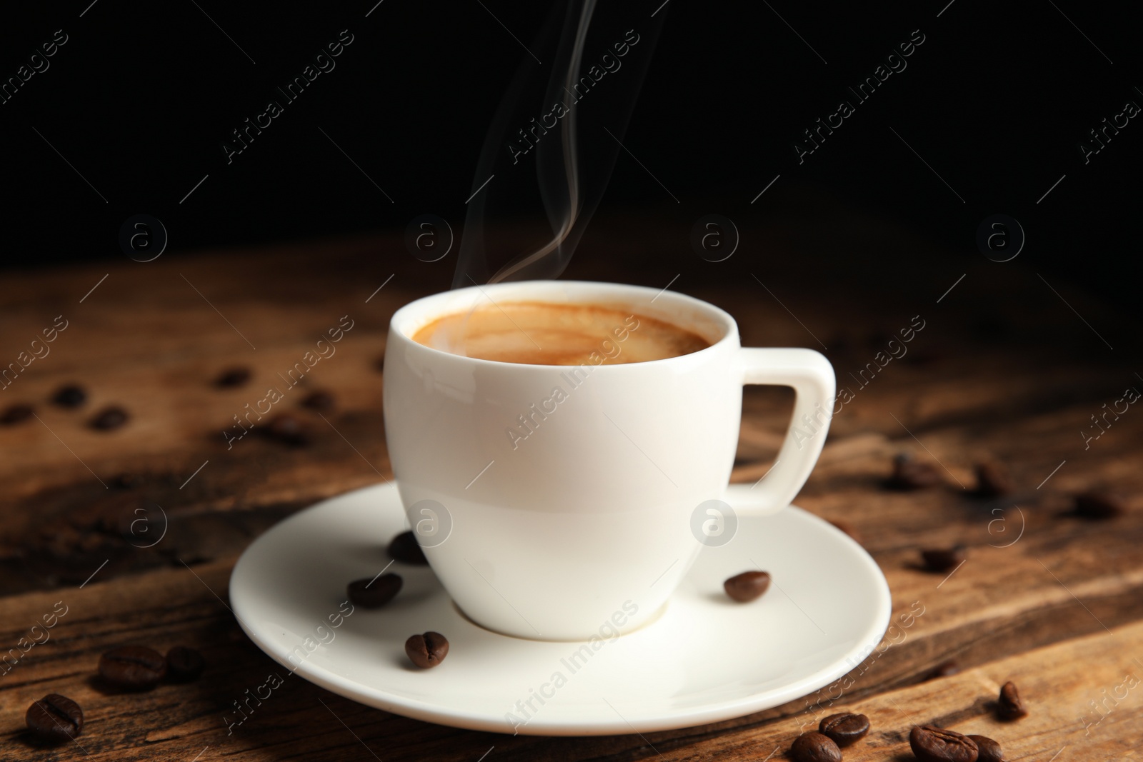 Photo of Cup of tasty coffee and beans on wooden table