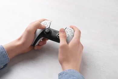 Man using wireless game controller at white table, closeup