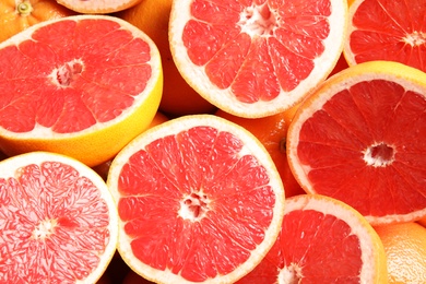 Many sliced fresh grapefruits as background, top view