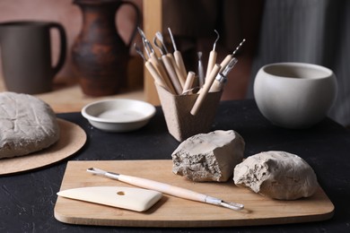 Photo of Clay and set of modeling tools on table in workshop