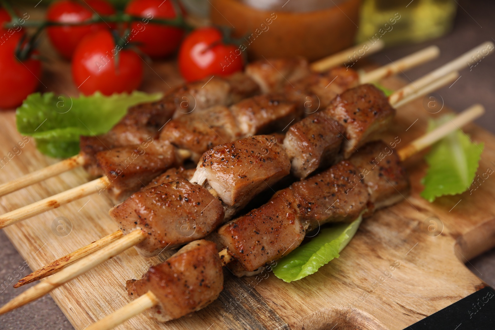 Photo of Tasty cooked marinated meat served with sauce and tomatoes on table, closeup