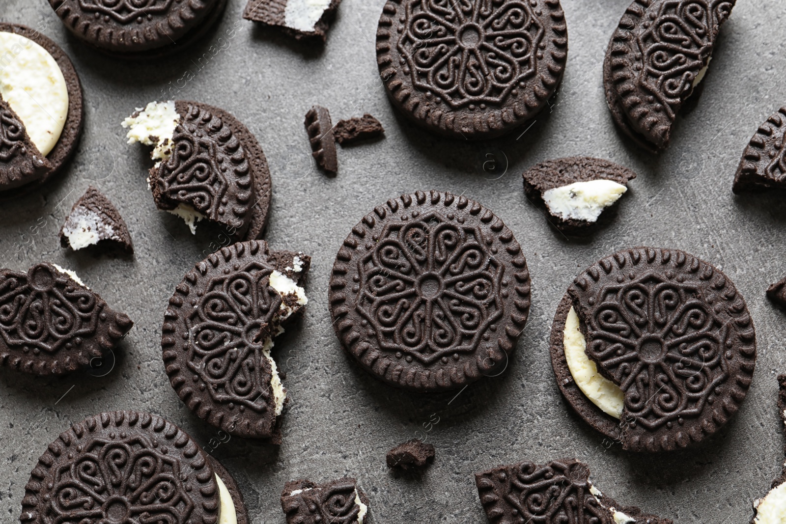 Photo of Tasty chocolate cookies with cream on grey background, flat lay