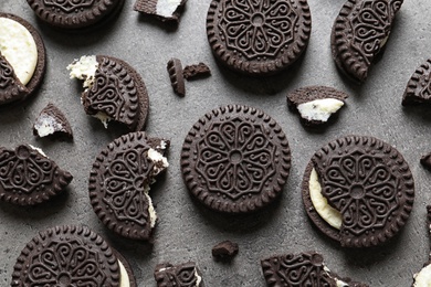 Tasty chocolate cookies with cream on grey background, flat lay