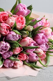 Photo of Bouquet of beautiful tulips on grey wooden table, closeup