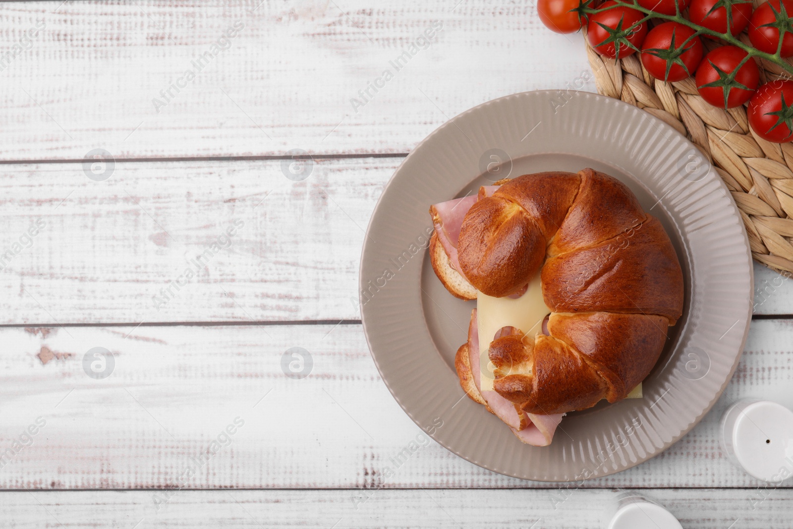 Photo of Tasty crescent roll with ham and cheese on white wooden table, flat lay. Space for text