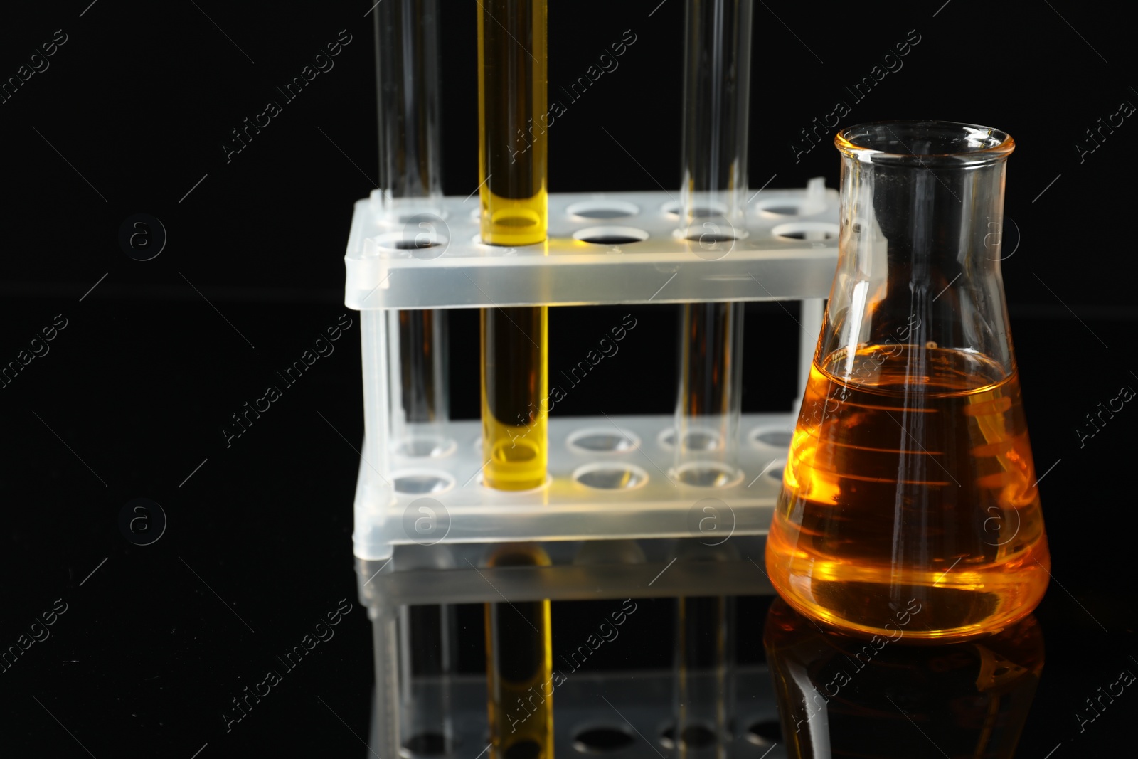 Photo of Laboratory glassware with different types of oil on black background