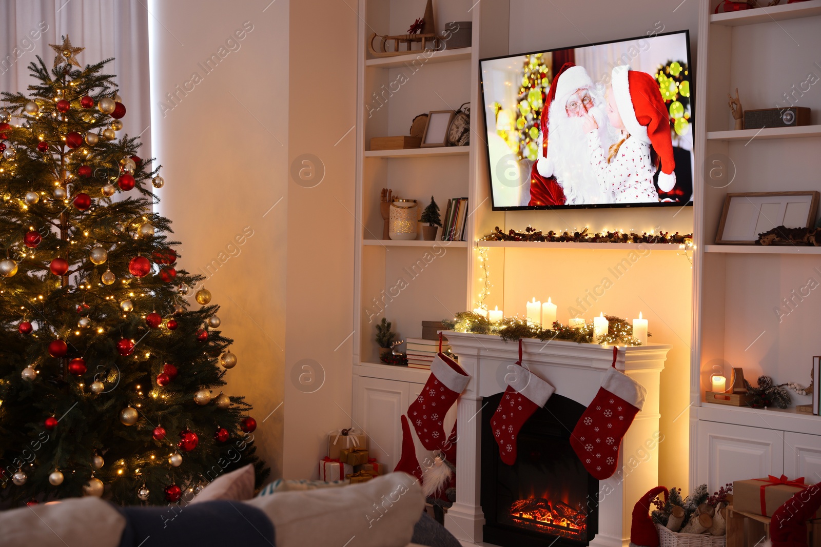 Photo of TV set with Christmas movie above fireplace in cosy room. Winter holidays atmosphere