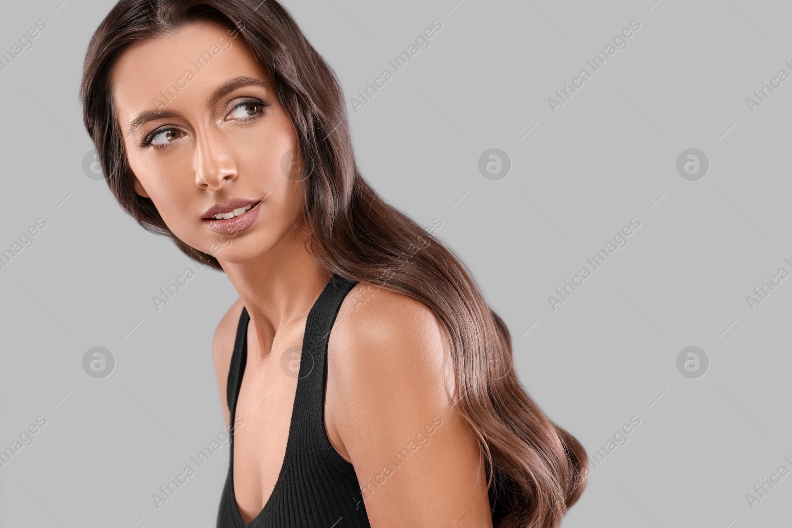 Photo of Hair styling. Beautiful woman with wavy long hair on grey background, space for text