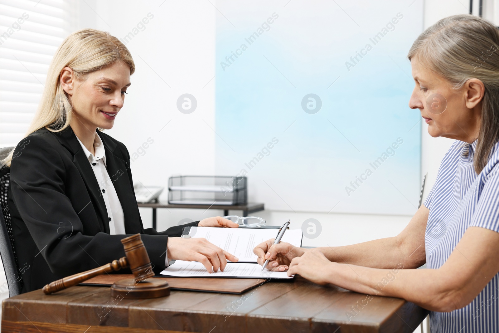 Photo of Senior woman signing document in lawyer's office